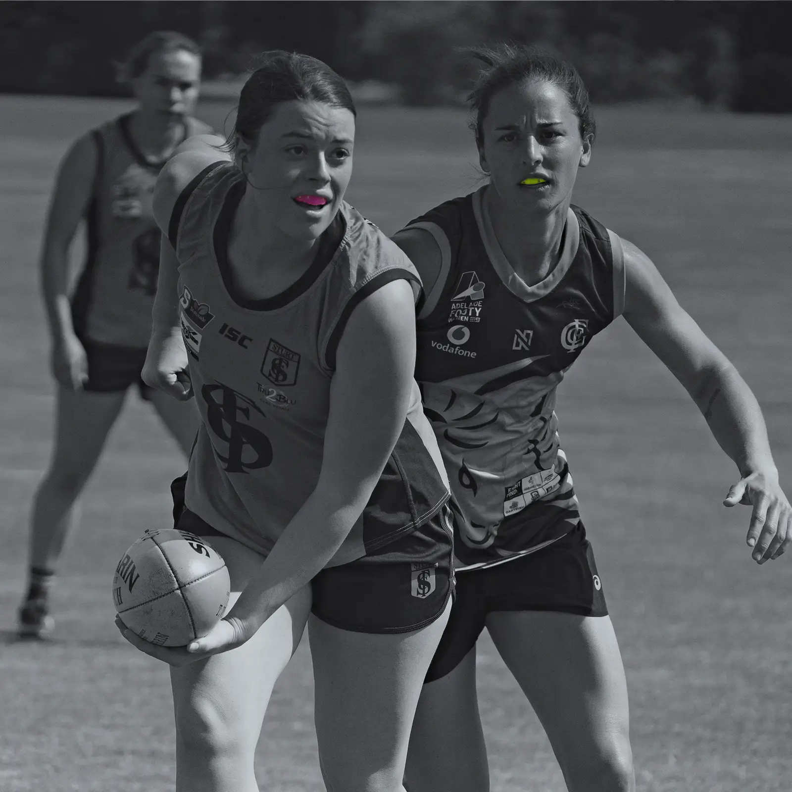 Female sports people wearing a mouthguards and playing Australian Rules Football
